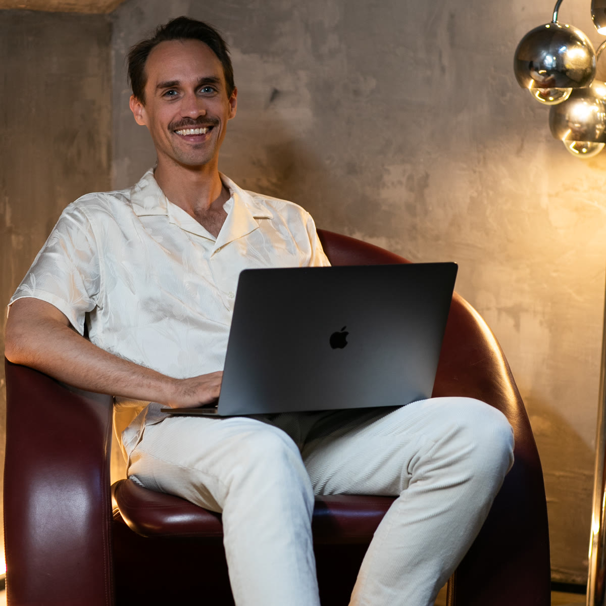 Benza Maman sitting in a leather chair with a laptop
